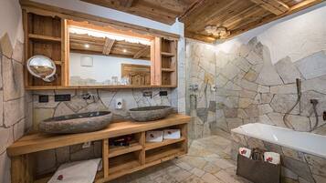 Un baño rústico con paredes de piedra, repisas de madera y un espejo grande.