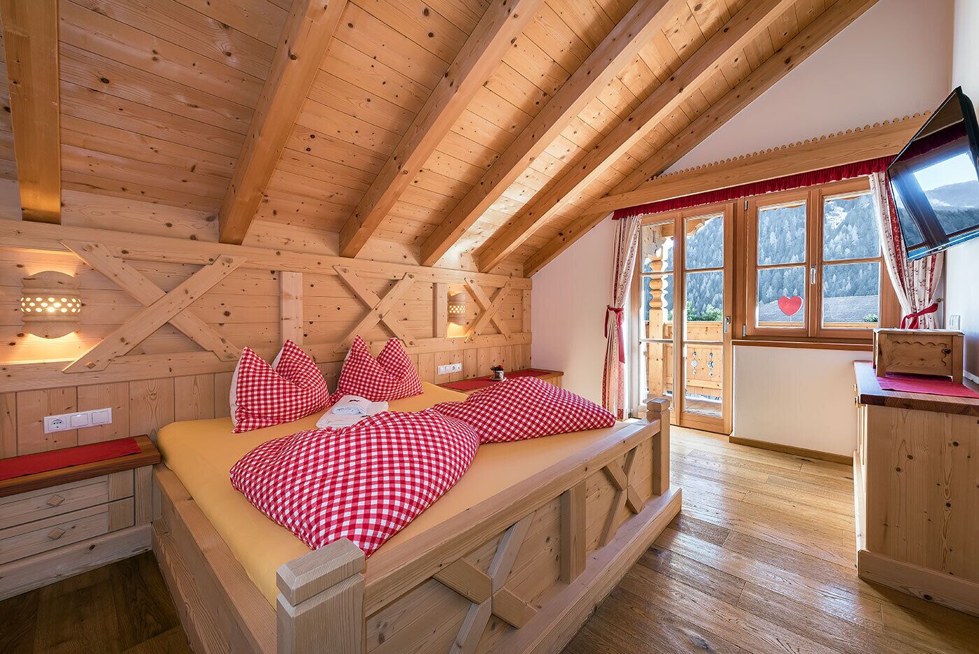 Ein gemütliches Holzhäuschen-Zimmer mit einem Bett, einem Schreibtisch und einem Fenster mit Bergblick.