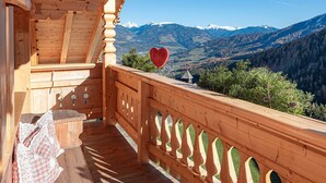 Un balcón de madera con vistas a montañas nevadas.