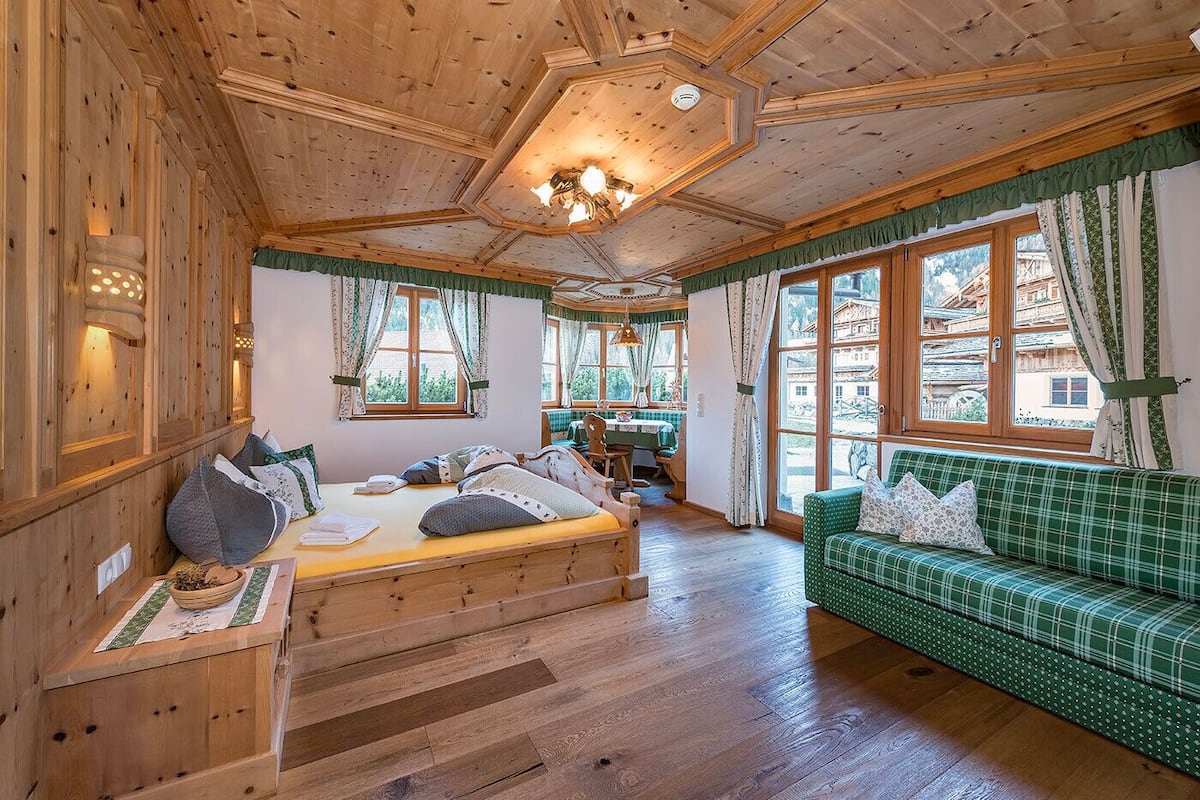 Eine Holzhütte mit einem Bett, einem grünen Sofa und großen Fenstern.