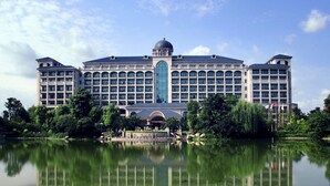 Un grande hotel con una cupola centrale e numerosi balconi, riflesso in una superficie d'acqua calma.