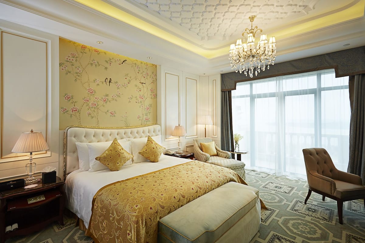 A luxurious hotel room with a large bed, a sitting area, and a view of the city.