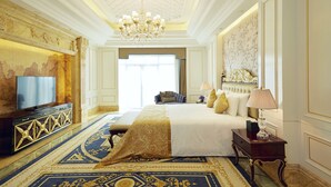 Una lussuosa camera d'albergo con un letto grande, un lampadario, una televisione e un pannello decorativo.