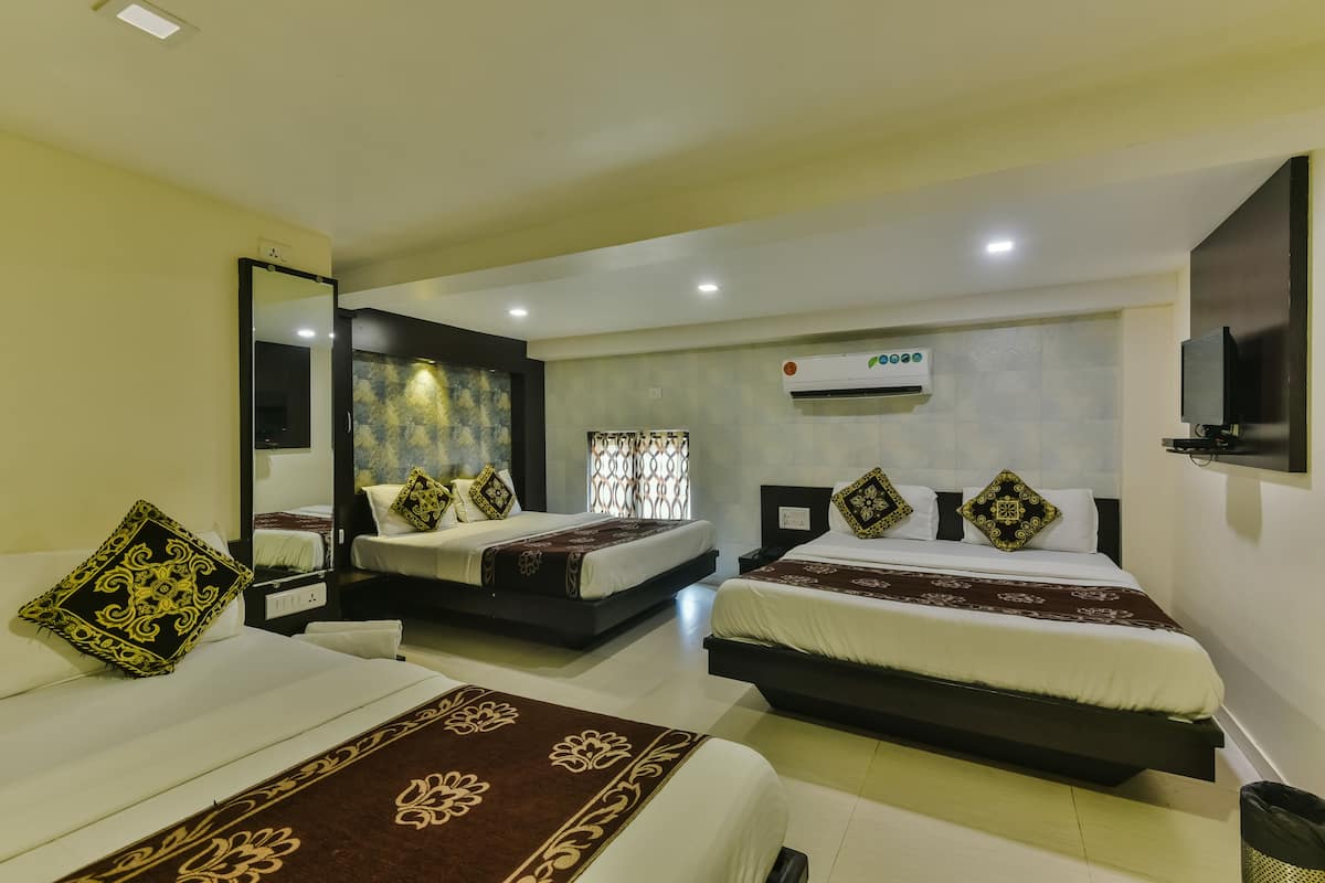 A hotel room with two beds, a large mirror, an air conditioning unit, and a television on the wall.