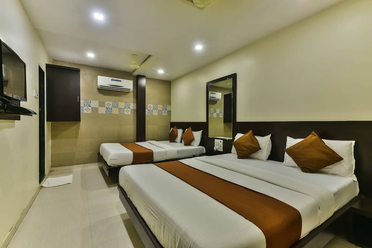 A hotel room with two beds, a ceiling fan, an air conditioning unit, and a tiled backsplash.