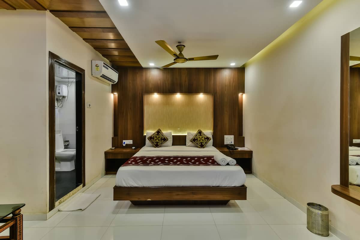 A modern bedroom with a wooden headboard, a ceiling fan, and a bedside table with a lamp.