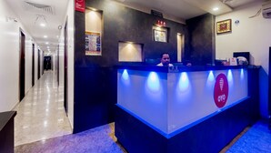 A hotel reception area with a modern design, featuring a reception desk with a logo, a clock, and framed awards on the wall. - Hotel Guest Inn Residency (Mumbai)