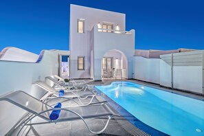 A modern pool area with lounge chairs and a clear blue sky. - Blue Senses Villas (Santorini)