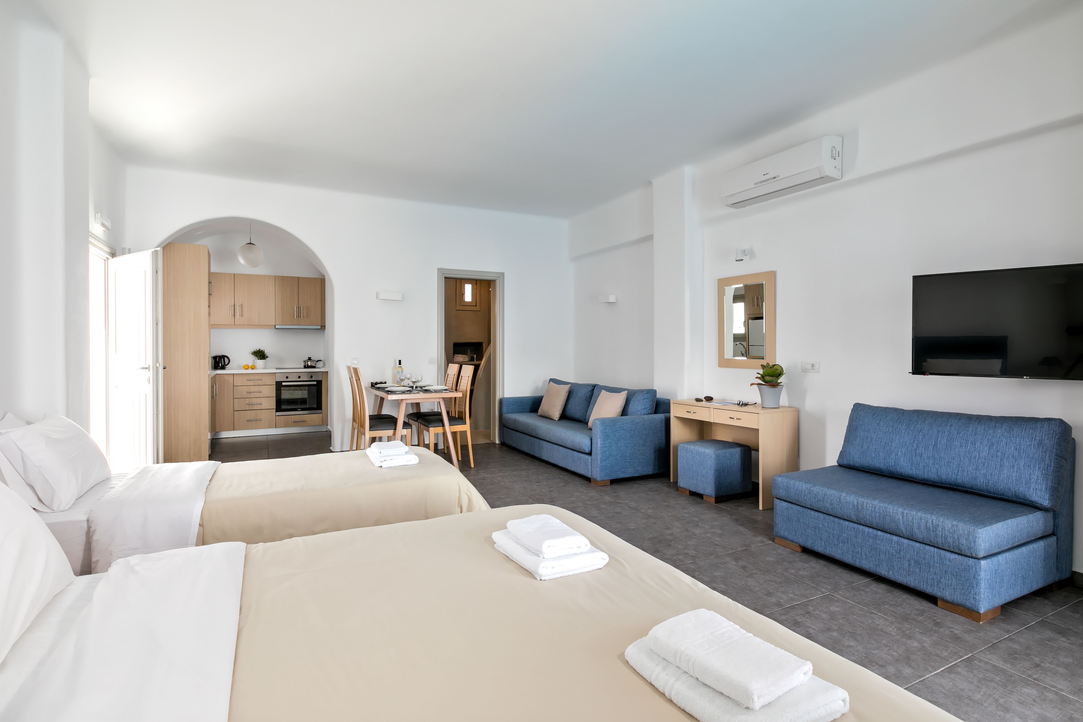 Habitación de hotel con dos camas, un sofá, un escritorio y una kitchenette.