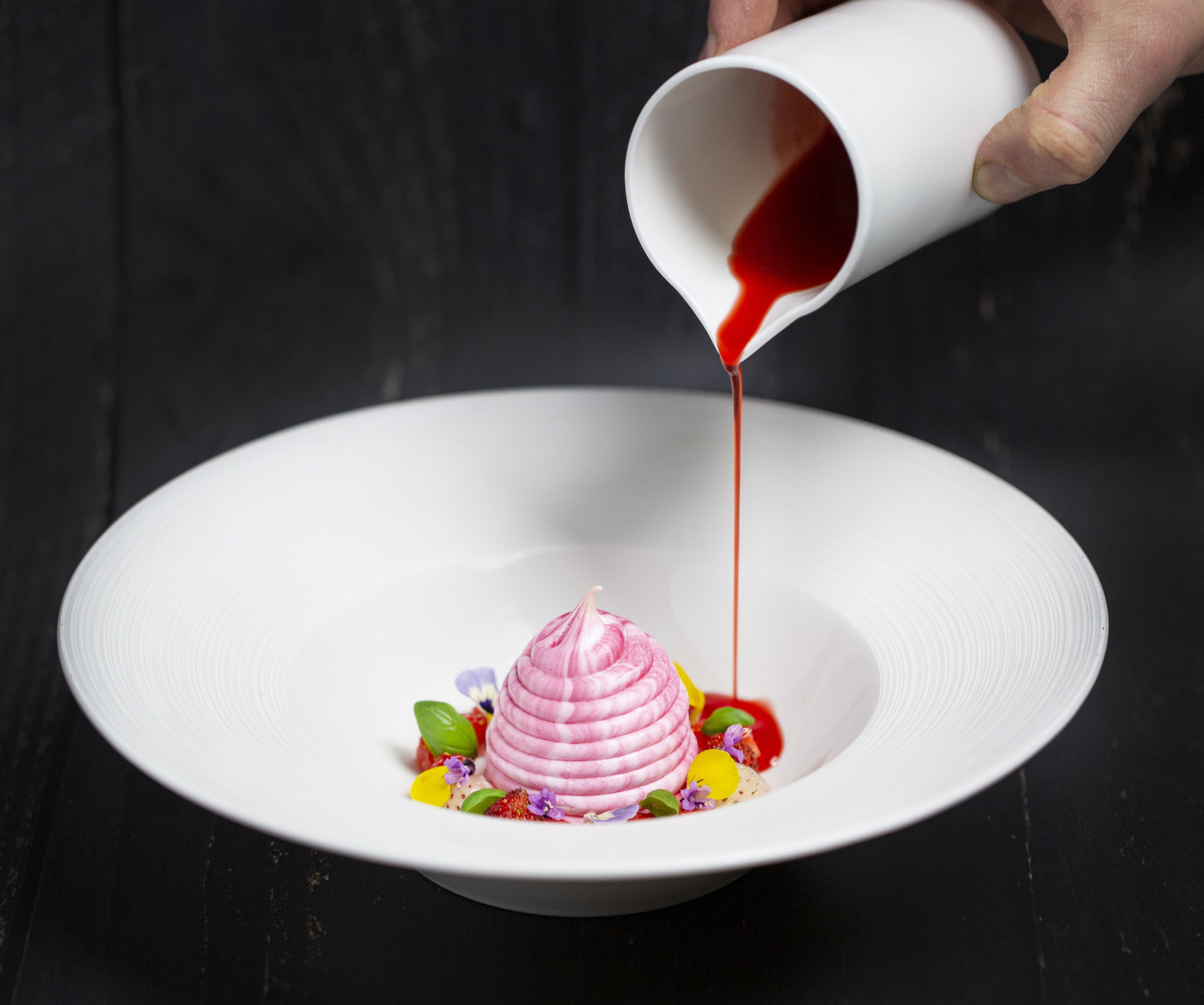 A white plate with a pink dessert and colorful garnishes.