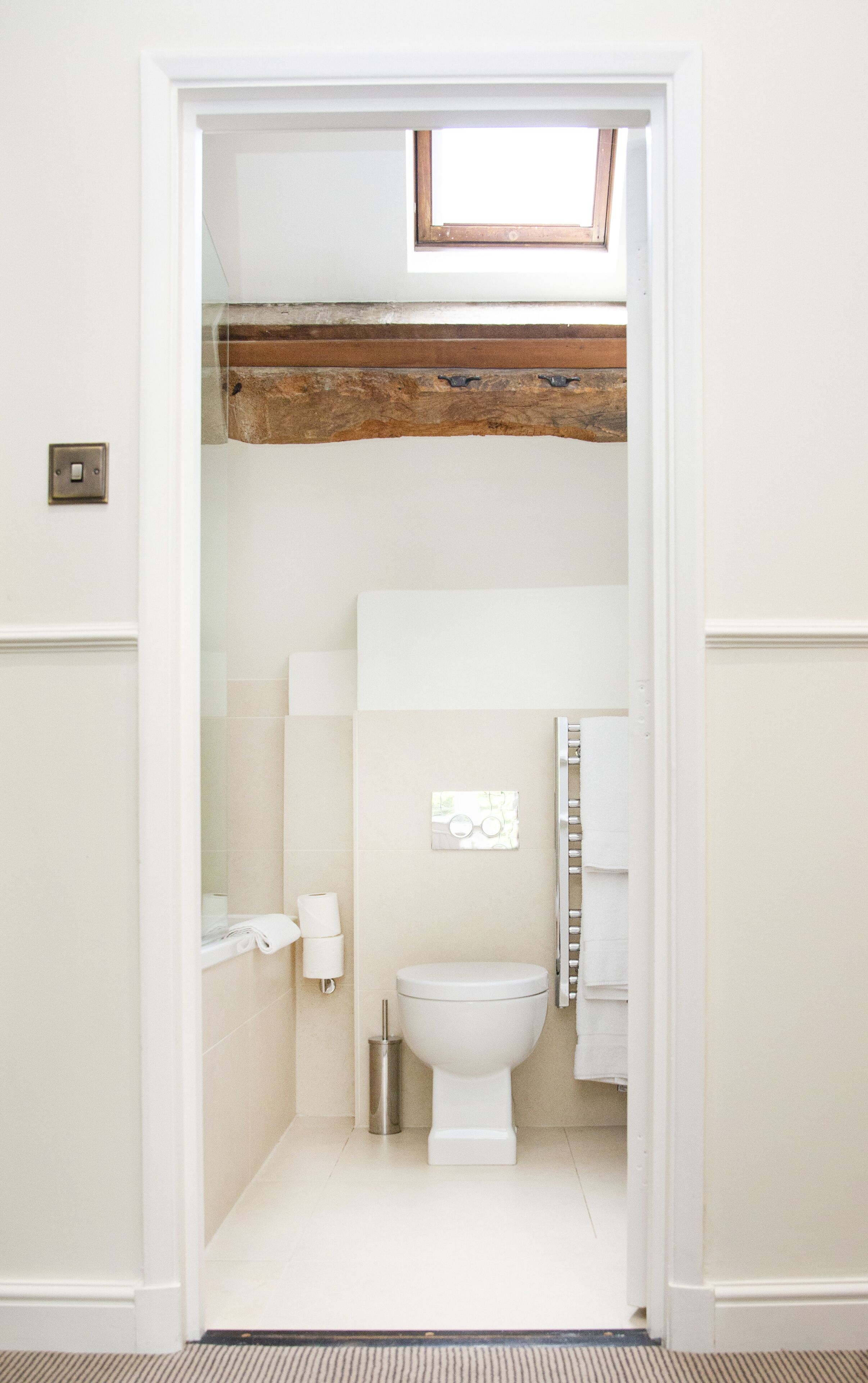 A bathroom with a white toilet, a towel rack, and a small trash bin.