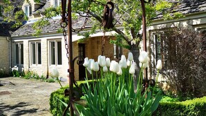 Un patio con una reja de hierro forjado, tulipanes blancos y muros de piedra.