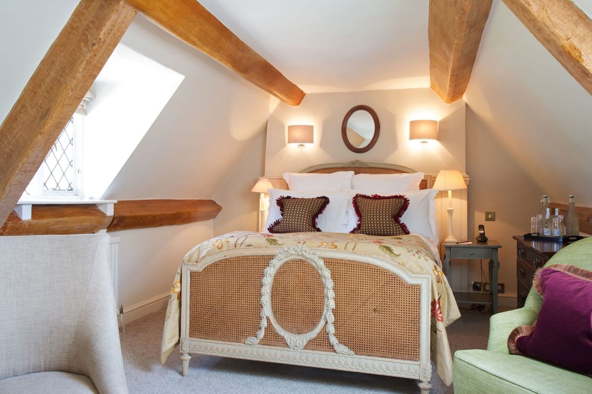 A bedroom with a rattan bed, two bedside lamps, a mirror, and a window with a view.