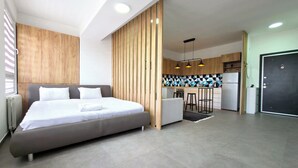 A modern hotel room with a large bed, a kitchenette, and a separate bathroom area. - Urban Serviced Apartments (Skopje)