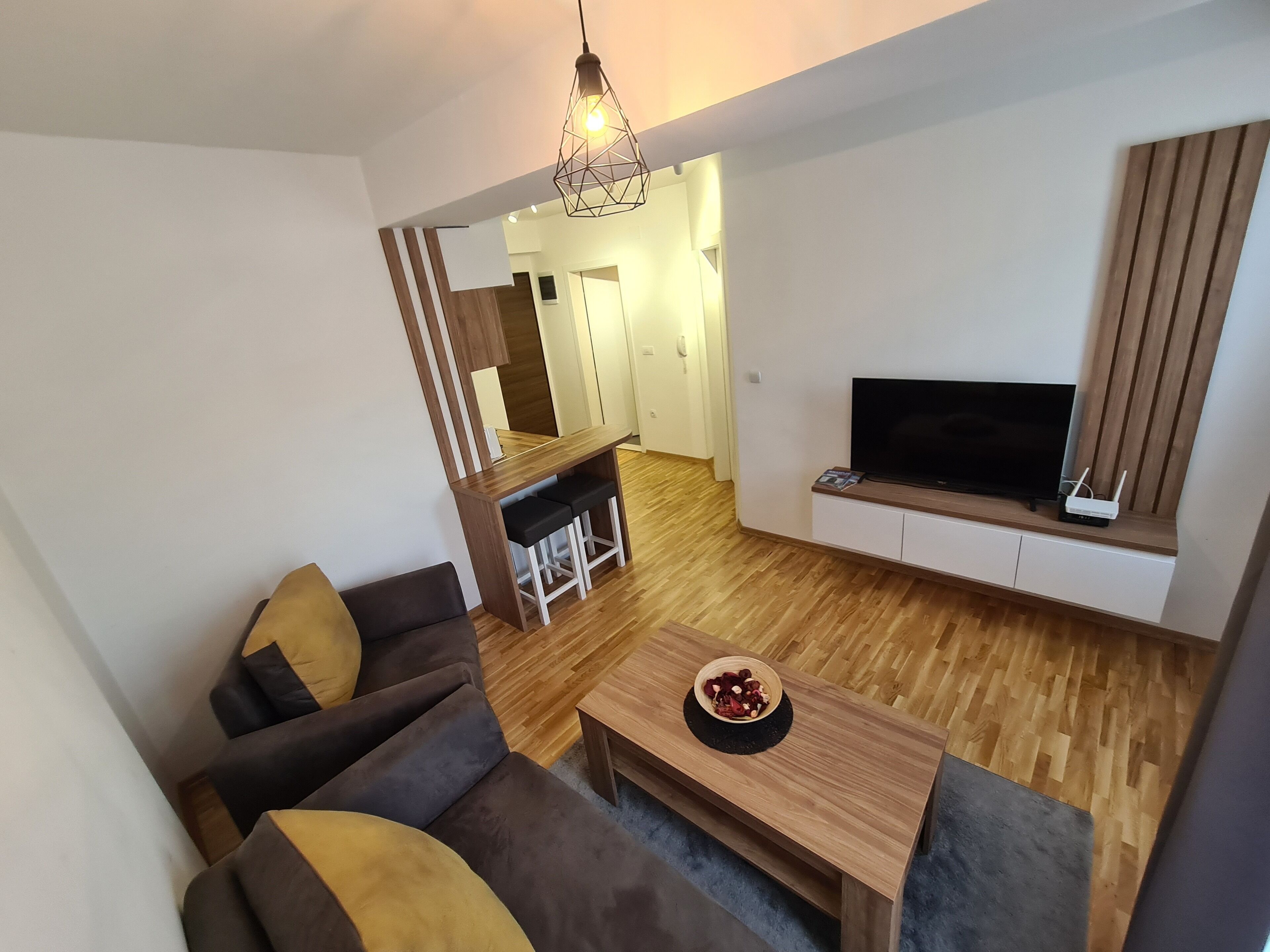 A modern living room with a sofa, coffee table, and a TV mounted on the wall.