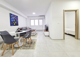 Una sala de estar moderna con comedor, sofá, televisión y un gran ventanal.