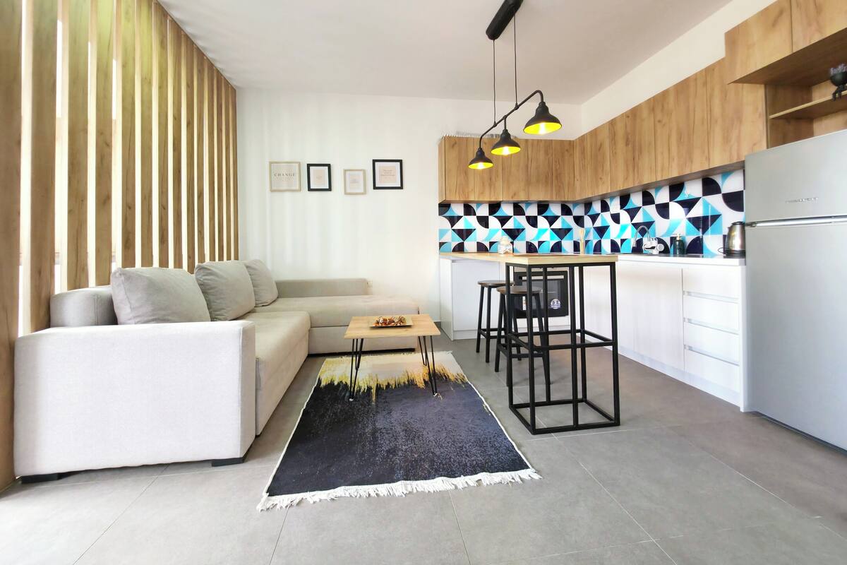 A modern kitchen with a built-in island, wooden cabinets, and a black and white patterned backsplash.