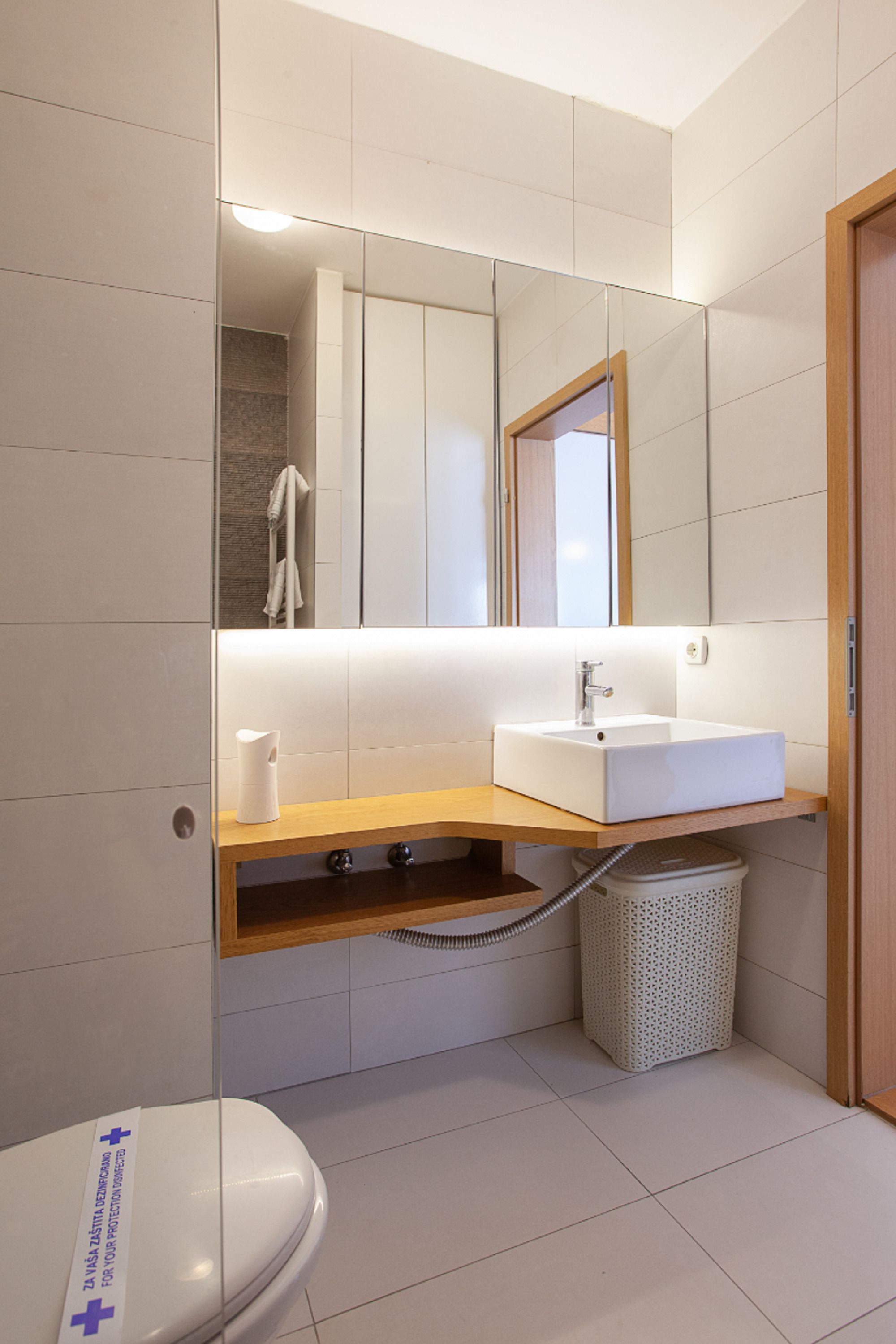 A modern bathroom with a white toilet, a sink with a mirror above it, and a shower area.