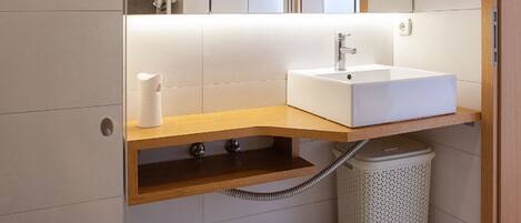 A modern bathroom with a white toilet, a sink with a mirror above it, and a shower area.