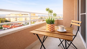 A balcony with a wooden table, a white cup, and a potted plant. - Urban Serviced Apartments (Skopje)