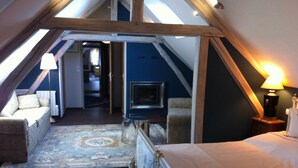 A cozy attic bedroom with a bed, a small table, a lamp, and a fireplace. - Chateau du Mesnil (La Vieille-Lyre)