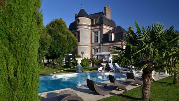 A large, luxurious house with a swimming pool, surrounded by well-maintained lawns and palm trees. - Chateau du Mesnil (La Vieille-Lyre)