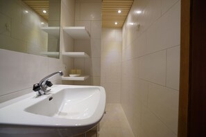 A bathroom with a white sink, a mirror, and a wooden ceiling. - Gästehaus Meusburger (Bezau)