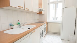 Una cocina con un lavamanos, lavadora y ventana.