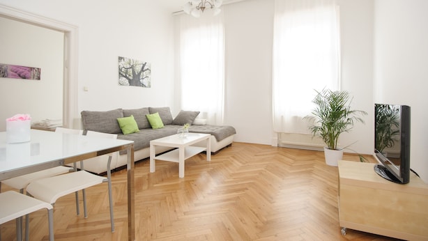 Una sala de estar moderna con un sofá, una mesa de centro y un televisor sobre un mueble.