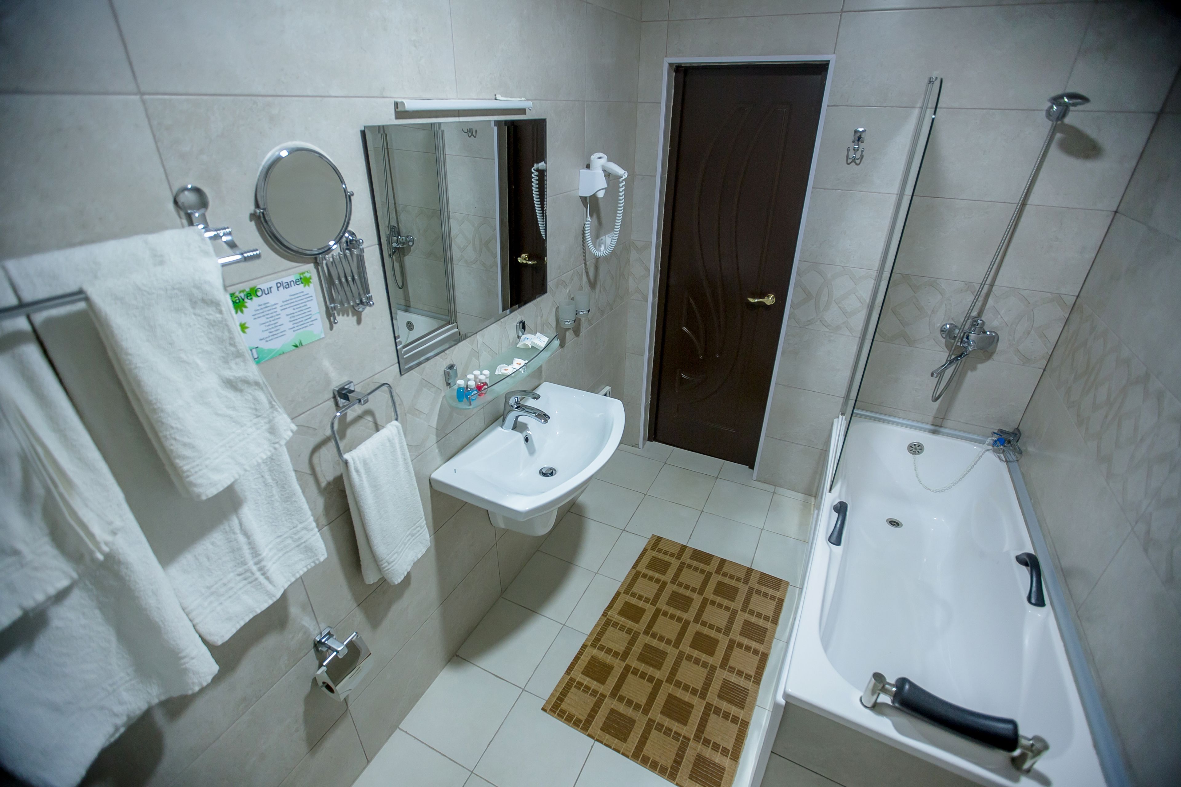 A bathroom with a sink, mirror, towel rack, and a shower area.