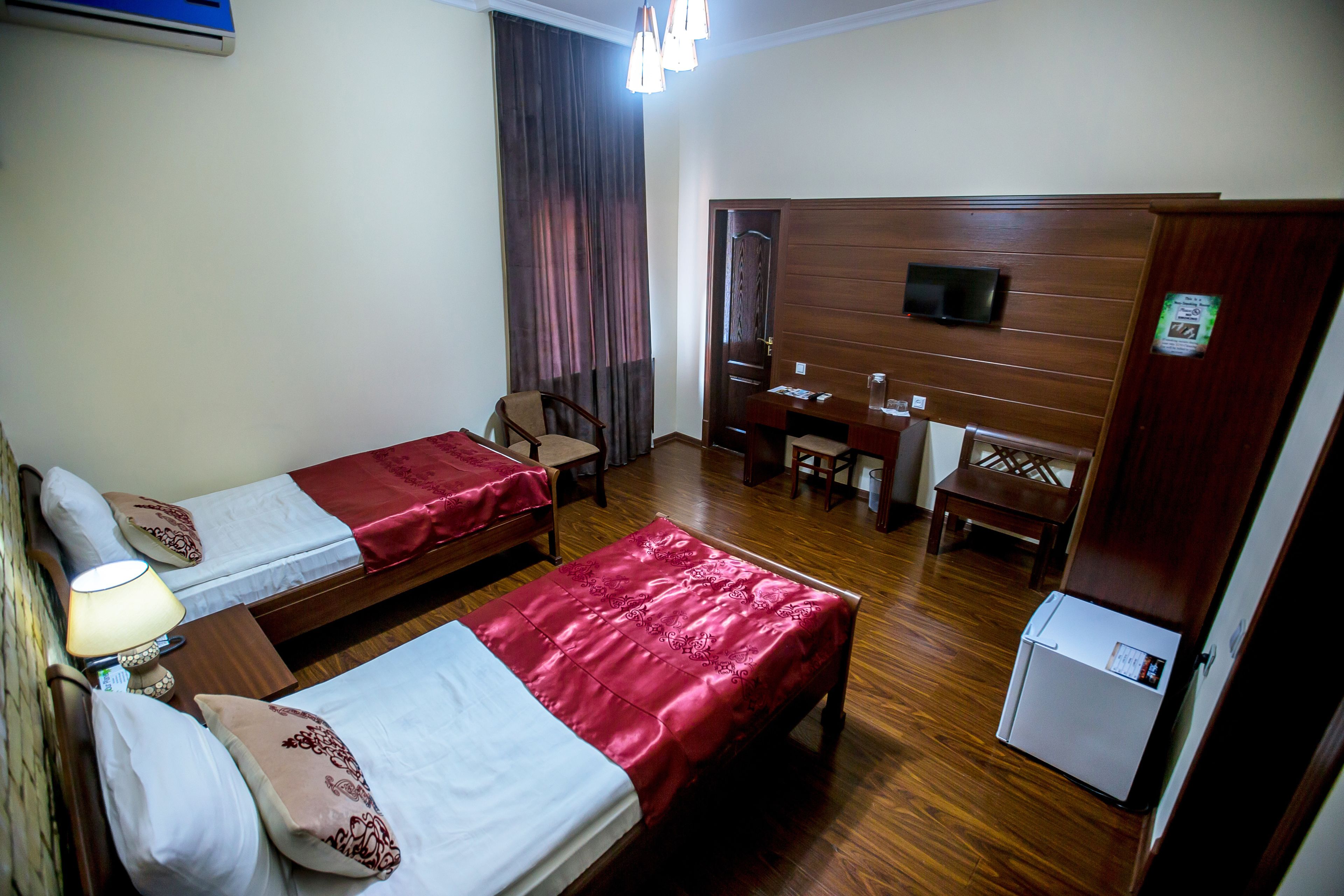 Une chambre d’hôtel avec deux lits, un bureau, une chaise, une télévision et un réfrigérateur.