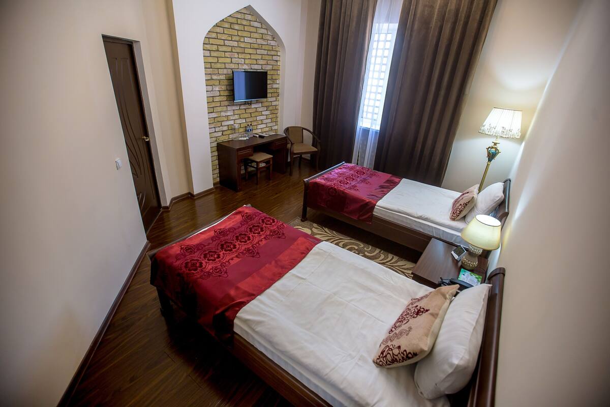 Habitación de hotel con dos camas, un escritorio, un televisor y una lámpara.