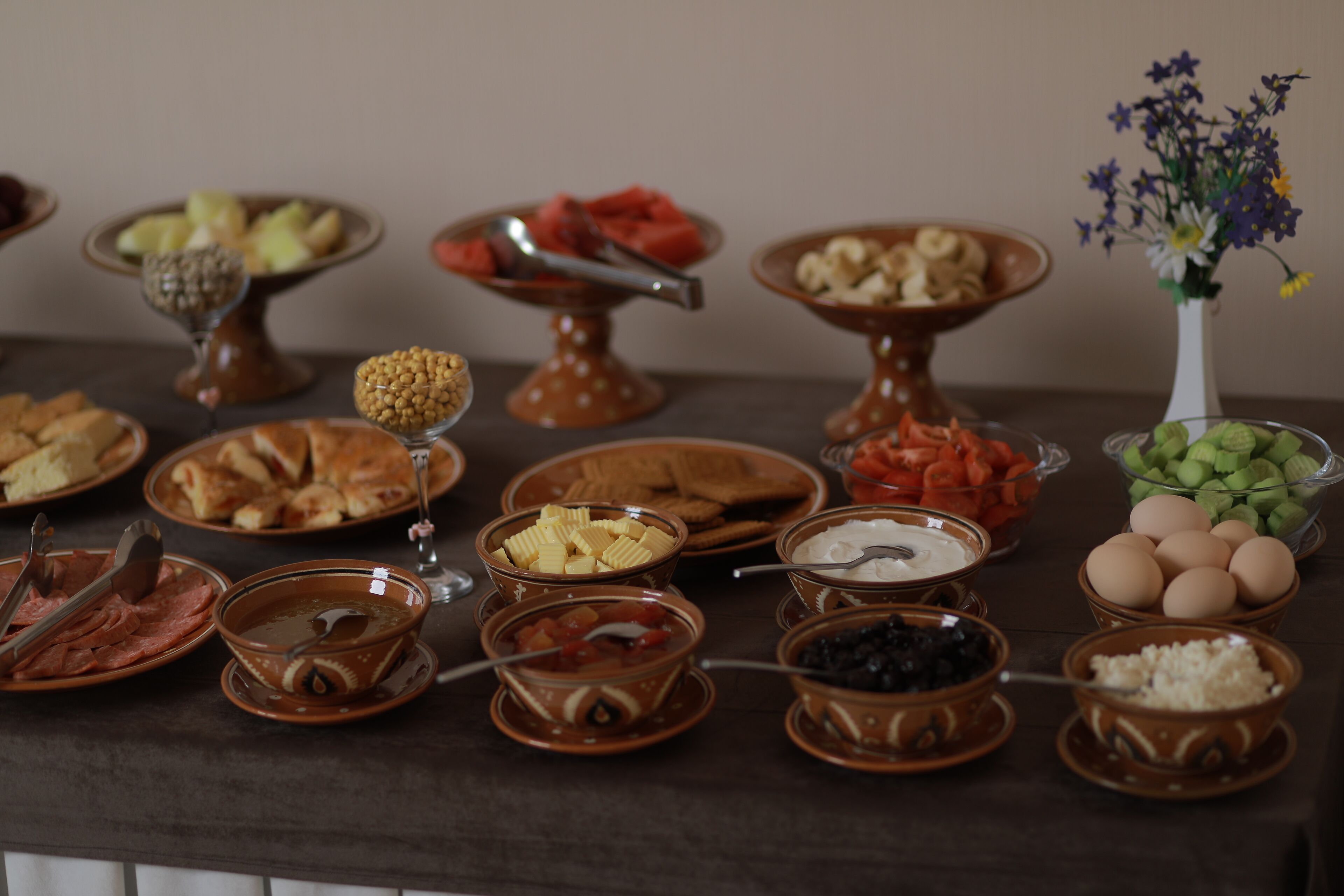 Una mesa con diferentes alimentos y un jarrón de flores.