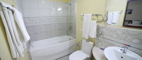 Un baño con ducha de vidrio, inodoro blanco y lavamanos con espejo.