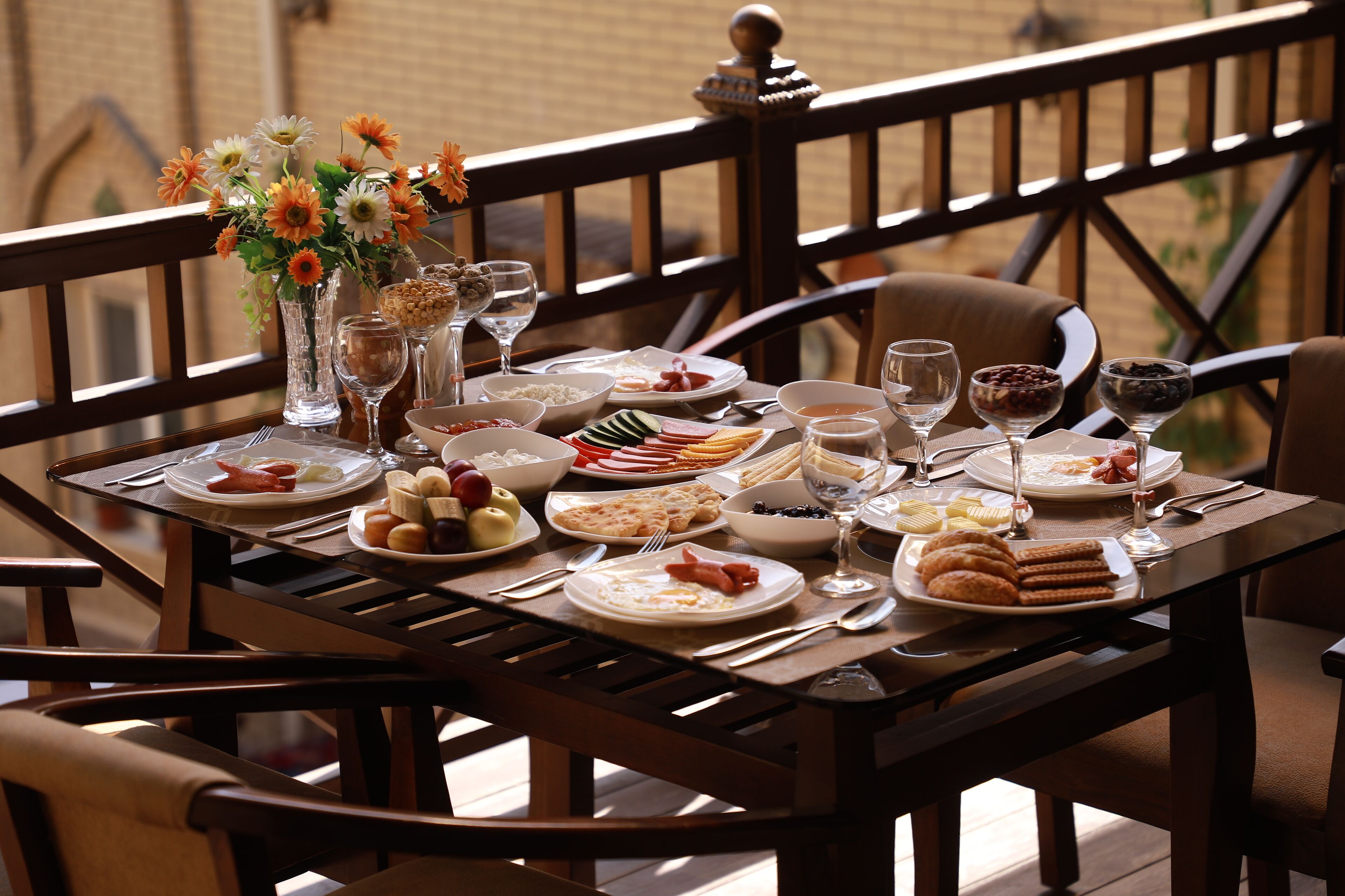 Una mesa de comedor preparada con diferentes platos, vasos y un jarrón de flores.