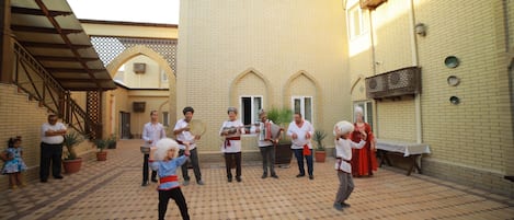 A courtyard with a tiled floor, a brick building, and a few people.