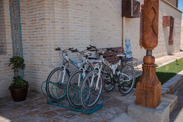 A brick building with a bicycle rack holding several bikes. - Khan Hotel Khiva (Khiva)
