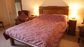 A bedroom with a large bed, two bedside tables with lamps, a chair, and a door.