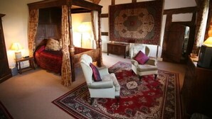 A traditional room with a four-poster bed, two armchairs, a red patterned rug, and a large decorative tapestry. - Blackmore Farm (Bridgwater)