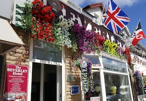 A hotel with a signboard for The Beverley Hotel, flags, and a variety of colorful flowers. - The Beverley Hotel (Blackpool)