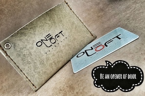 A metal door handle with the text "ONE COFT" and a badge with the text "BE AN OPENER OF DOOR". - Oneloft Hotel (Karon)
