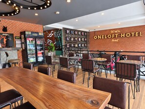 A modern hotel restaurant with brick walls, wooden tables, and a neon sign. - Oneloft Hotel (Karon)