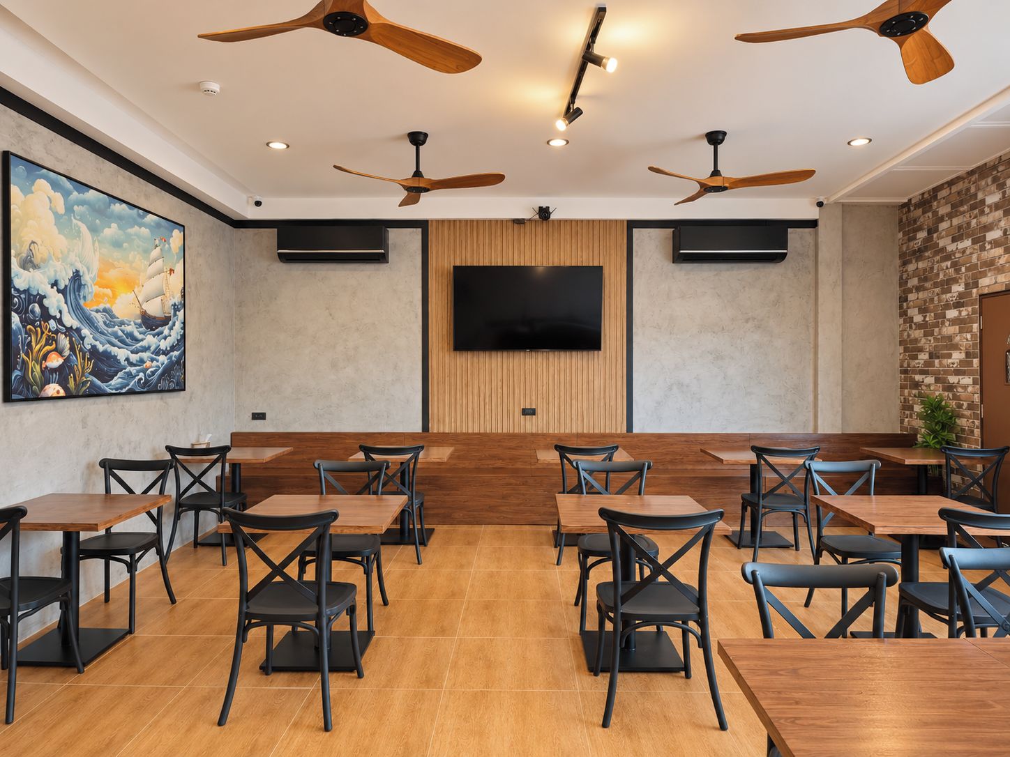 A conference room with multiple tables and chairs, a large painting on the wall, and ceiling fans.