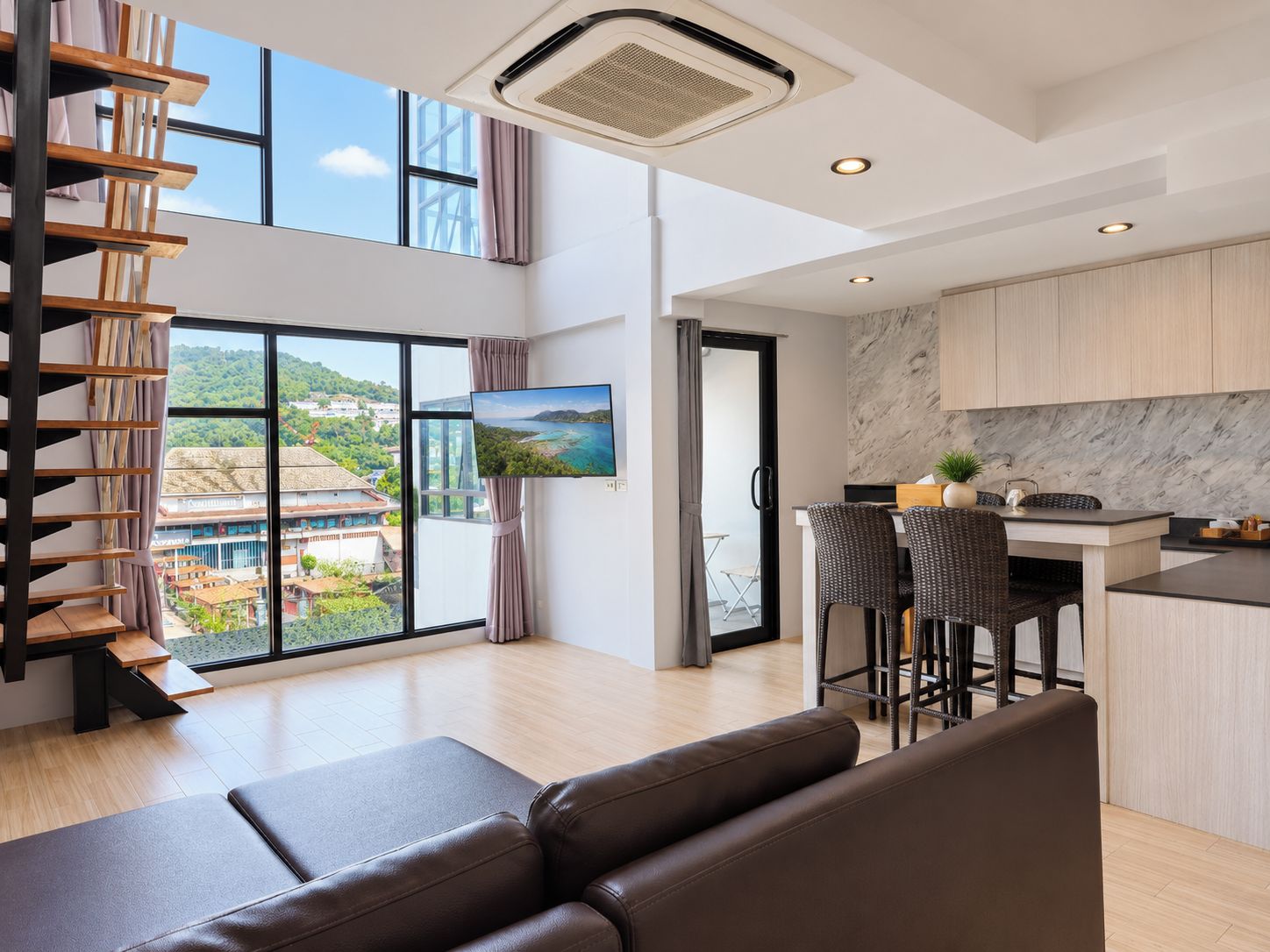 A modern living room with a sofa, a dining area with chairs, a kitchen with marble backsplash, and a large window with a view.
