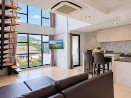 Una sala moderna con sofá, un comedor con sillas, una cocina con salpicadero de mármol y un ventanal con vistas.