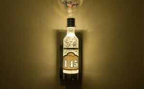 A bottle of liquor with a label displaying the number 145, mounted on a wall. - Oneloft Hotel (Karon)