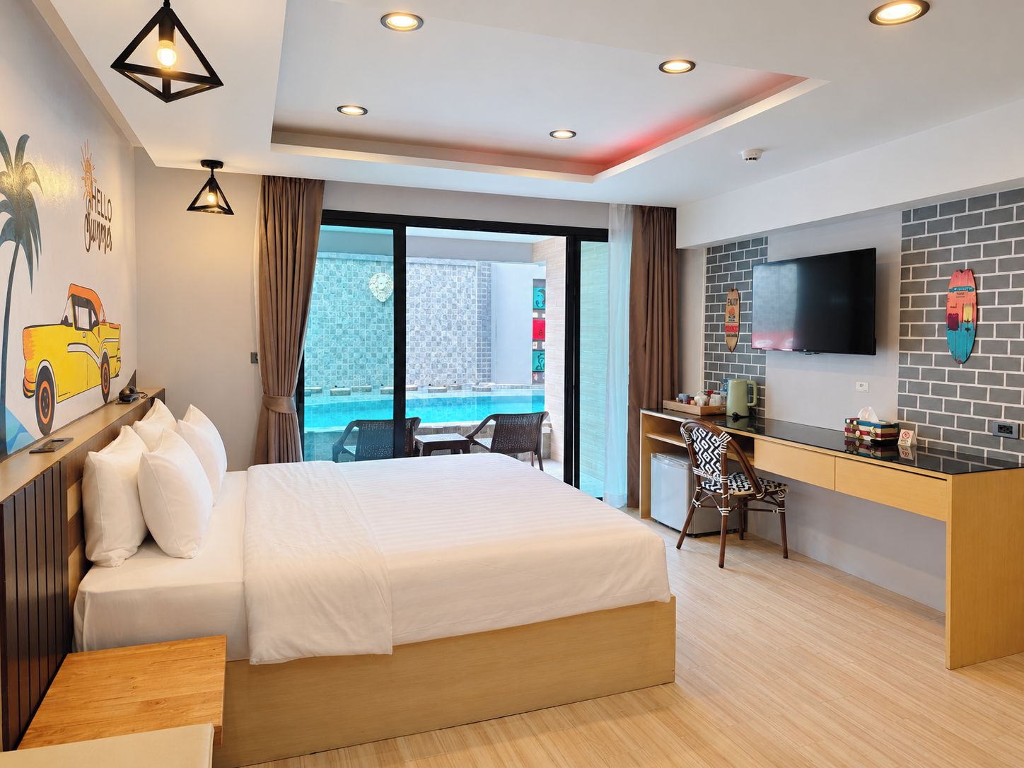 Een hotelkamer met een bed, bureau, televisie en uitzicht op een zwembad.