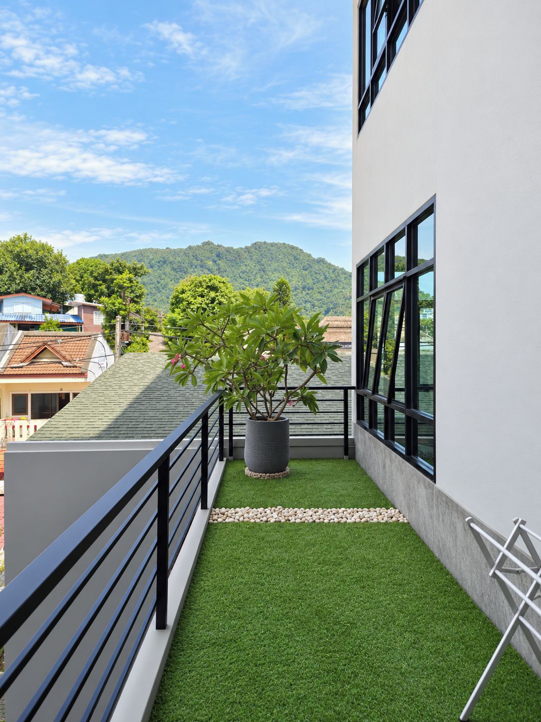 Ein Balkon mit Kunstrasen, einem Blumentopf und Blick auf einen Berg.