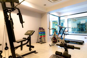 A gym with a bench press, dumbbells, a stationary bike, and a treadmill.
