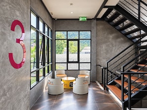 Een modern interieur met een groot nummer 3 op de muur, een trap en zithoeken met 'ONE LOFT' branding.